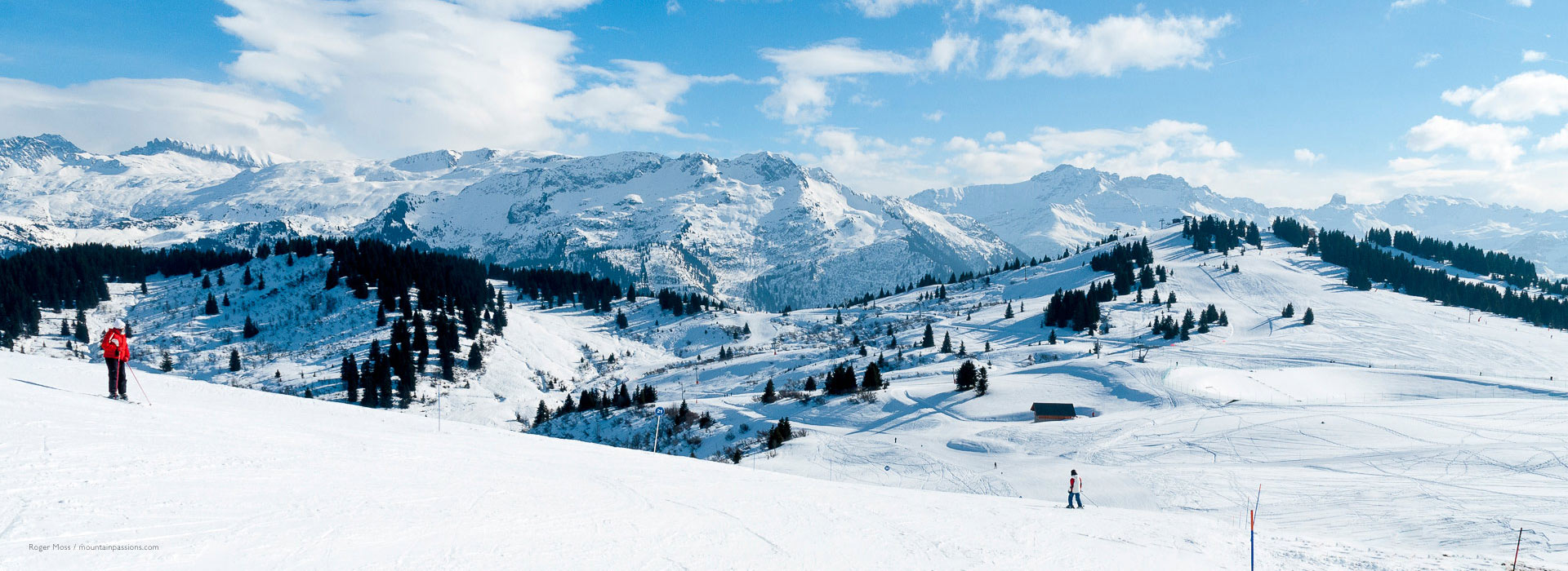 Skiers on wide piste with panoramic view of mountain landscapes at Les Saisies