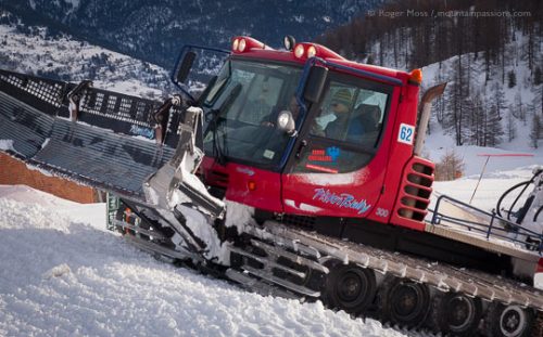 Piste groomer operator instruction, with mountain backdrop