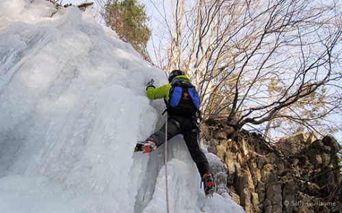 Close-up of climber nearing top of frozen waterfall