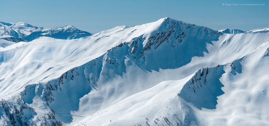 Wide view towards snow-covered mountains, showing ski-pistes between Pra Loup and Val d'Allos
