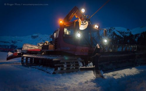 Night view of winch-equipped piste groomer with lights