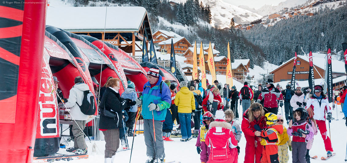 Skiers and other visitors at ski show with village and mountainside in background