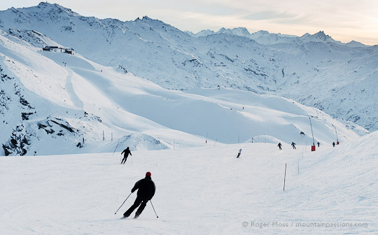 Skiers on last run of the day, with setting sun at Les Menuires