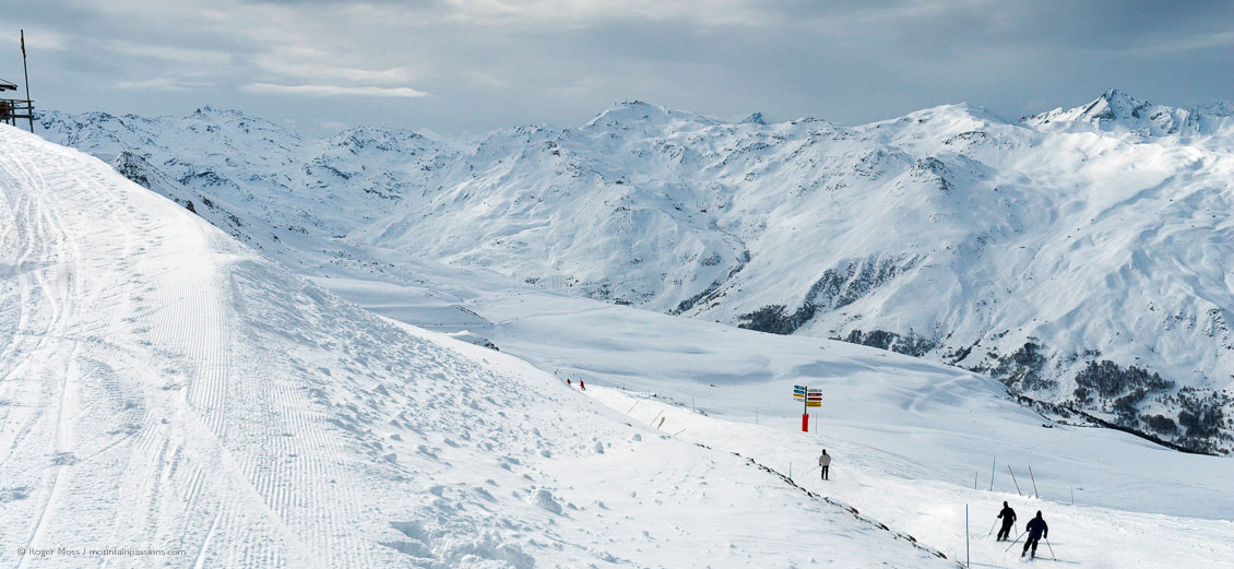 Wide overview of skiers setting off into big mountain landscape