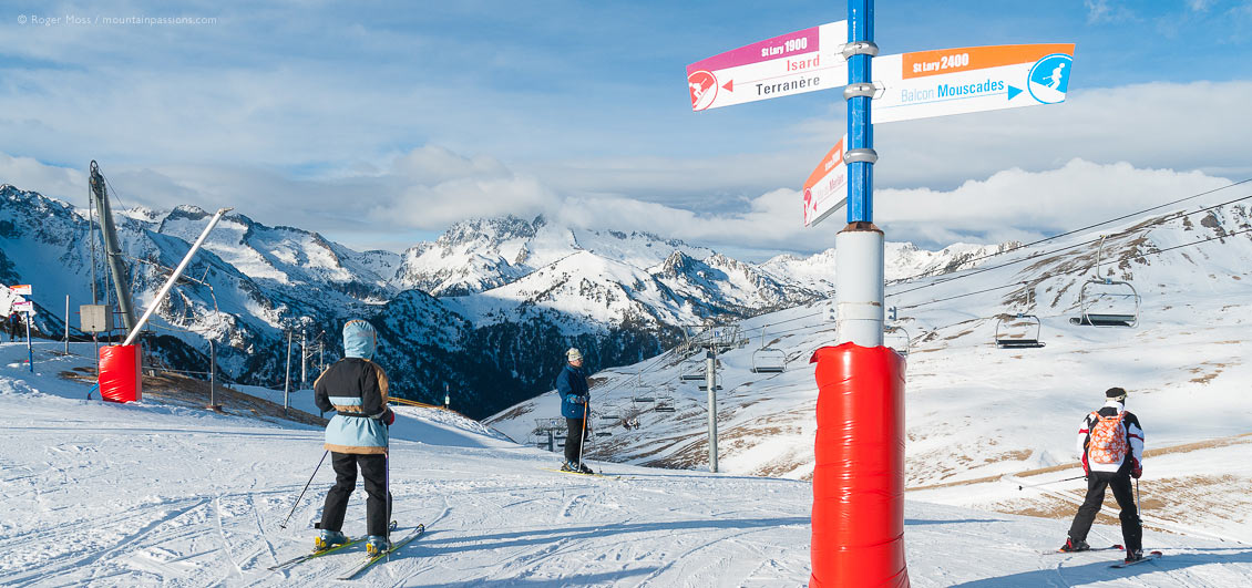 View of skiers passing piste signs at Saint Lary Soulan