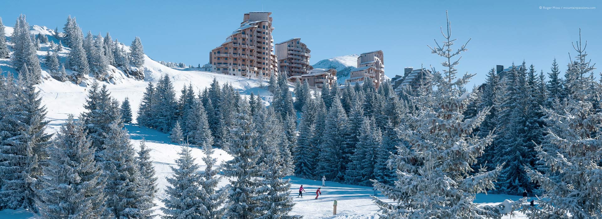 Skiers on tree-lined piste below Avoriaz ski resort