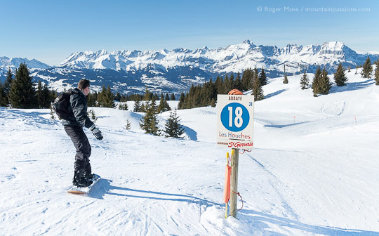 Rear view of snowboarder passing piste sign