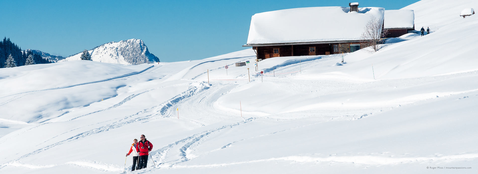 Snow-shoeing on mountain with traditional chalet, La Toussuire, French Alps