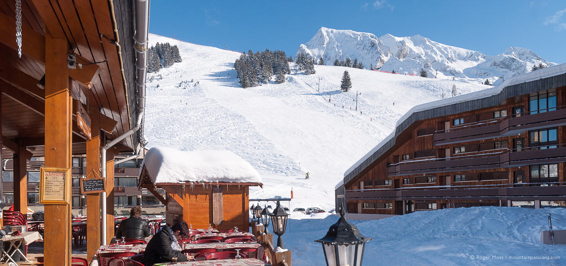 Wide view from restaurant terrace of mountain with skiers at La Clusaz
