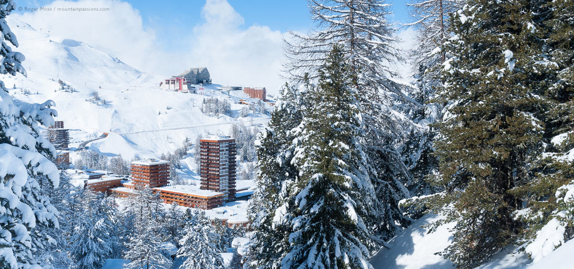 Elevated view through snow-covered trees of Plagne Centre ski village, La Plagne