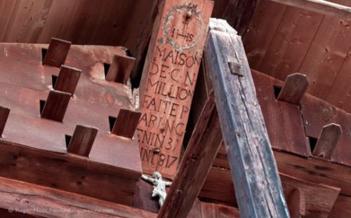 Detail of traditional Alpine chalet roof timbers with date inscription.