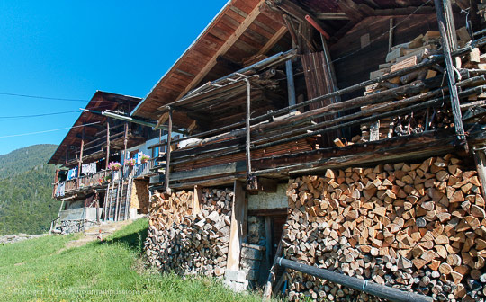 View past firewood stacked on front of grenier to traditional mountain chalet