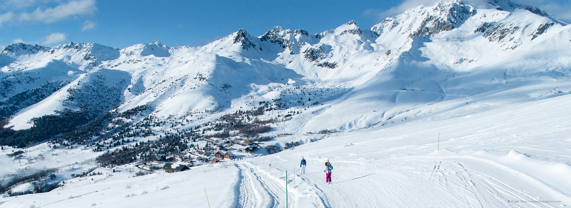 Wide view of skiers with deep snow above mountain village at Saint Francois Longchamp.