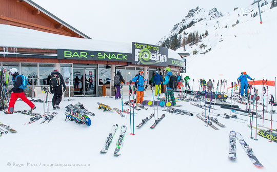 Wide view of skiers and skis outside mountain snack bar in Flegere ski area.
