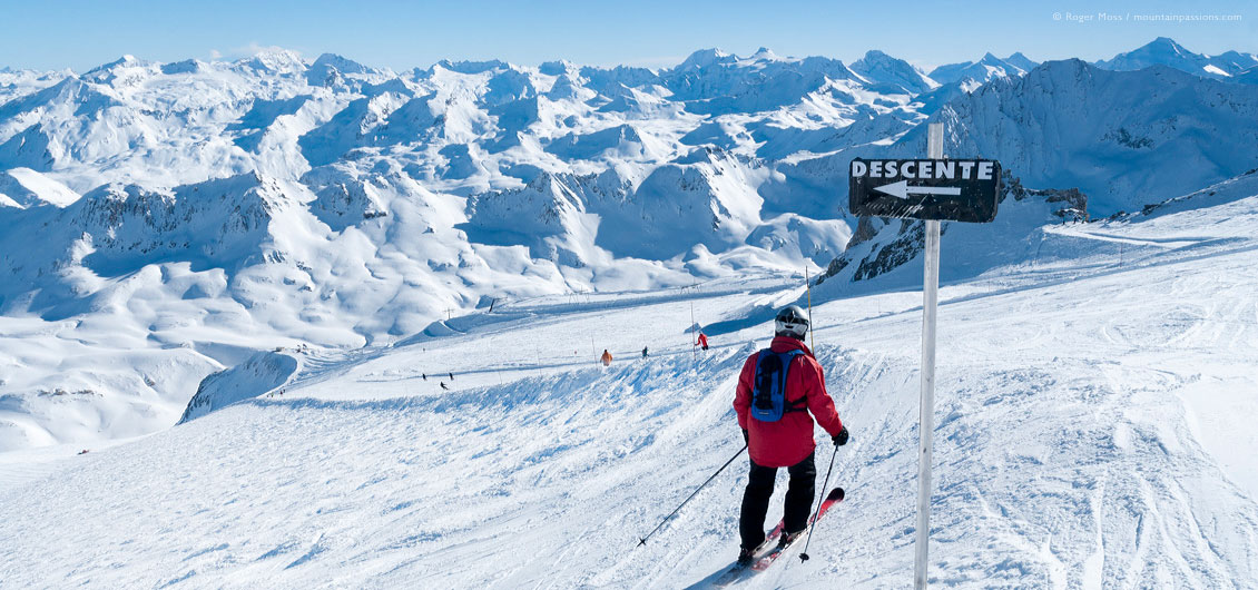 Wide view above glacier, showing skiers and mountain landscape