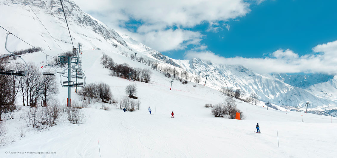 Wide view of family skiers from chair-lift, showing Albiez-Montrond ski terrain