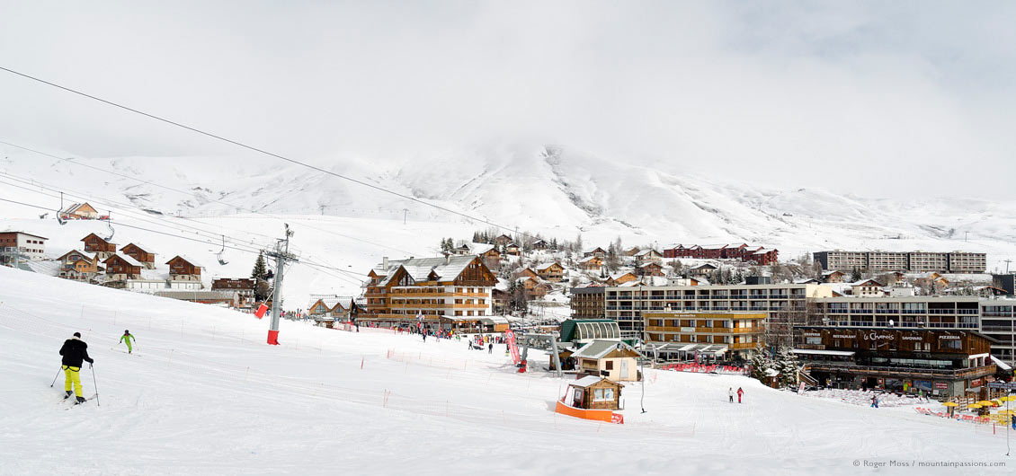 Wide view of skier returning to ski village of La Toussuire, Les Sybelles, Maurienne, French Alps.