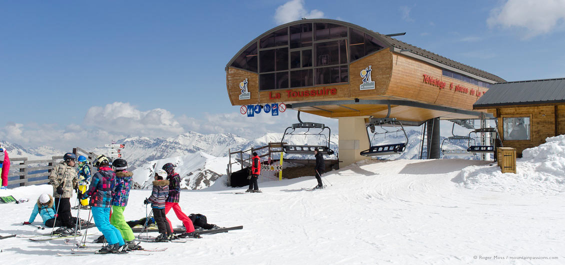 Group of skiers beside high-speed chair-lift at La Toussuire, Les Sybelles, Maurienne, French Alps.