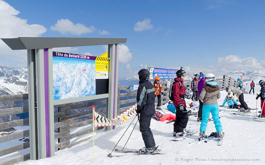 Skiers looking at piste map sign beside chair-lift at La Toussuire, Les Sybelles, French Alps