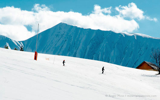 Two skiers on wide piste on sunny day