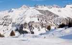 View of three skiers descending piste among rugged mountain scenery