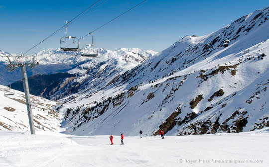 High view of skiers under chairlift with big mountain view, La Toussuire, Les Sybelles, French Alps