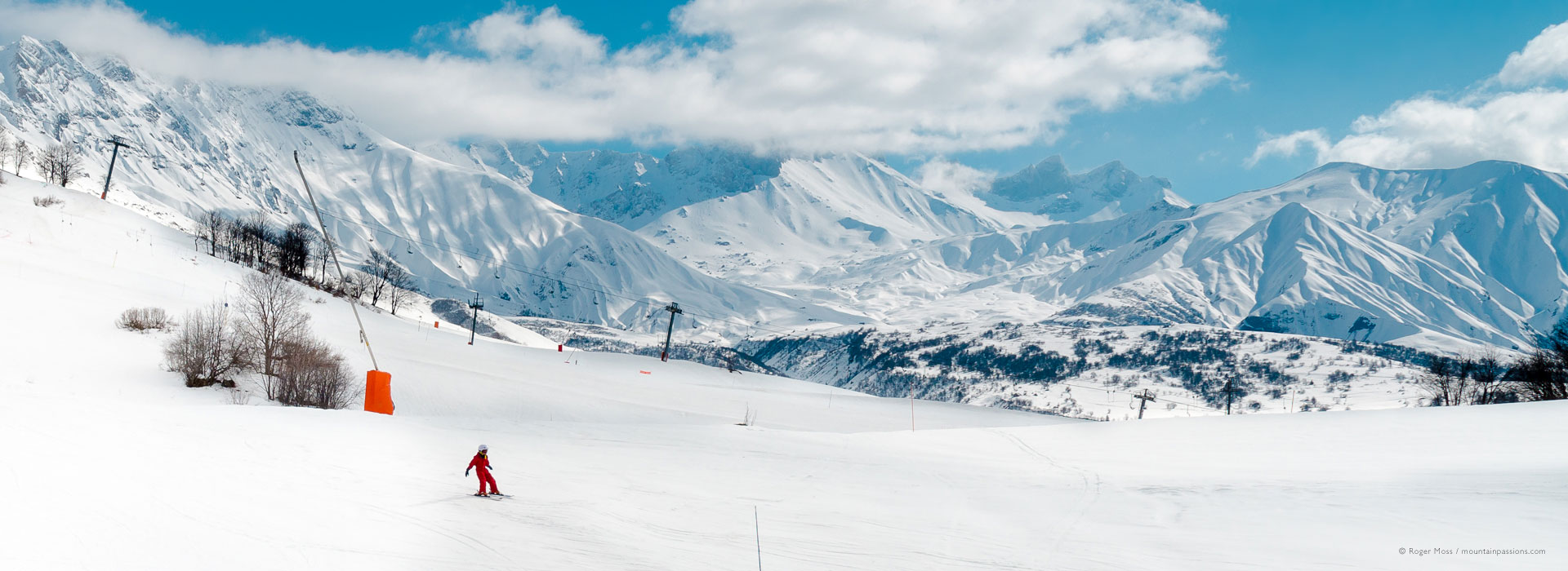 Wide view of child skier with big mountain backdrop at Albiez-Montrond.