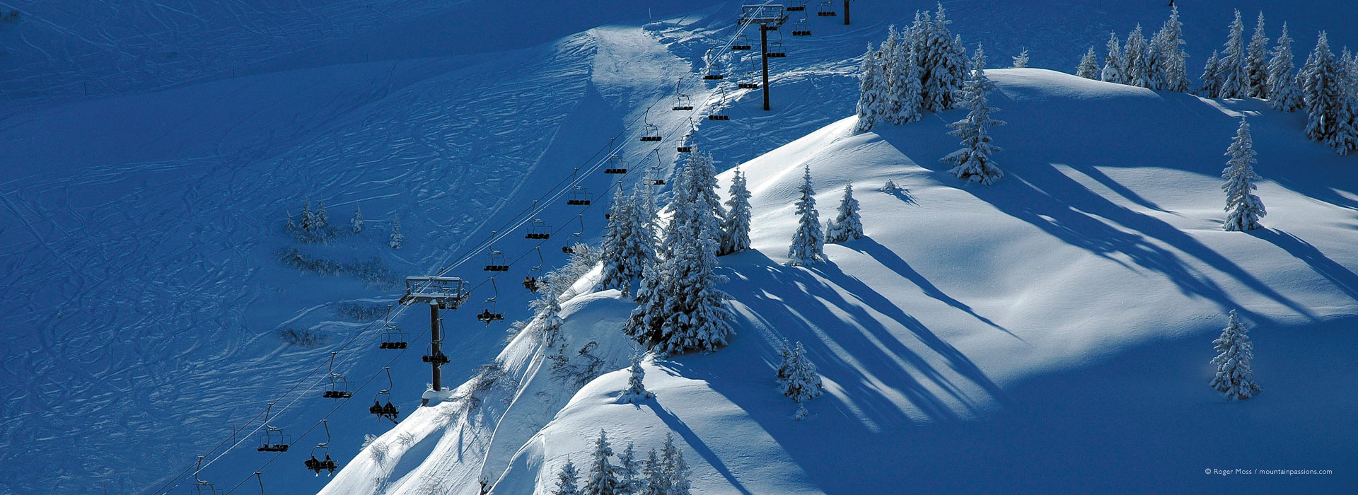 High view of skiers and chairlift, with long morning shadows