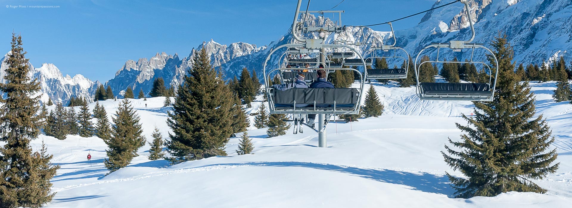 View from chair-lift of ski terrain with trees and mountains