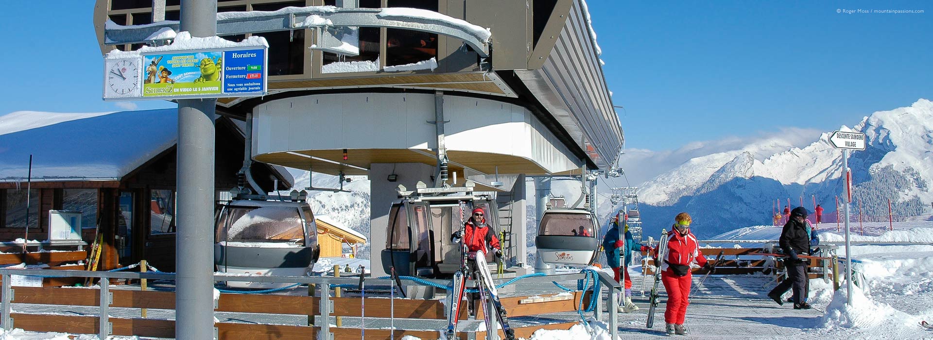 Skiers leaving top station of high-speed gondola ski lift