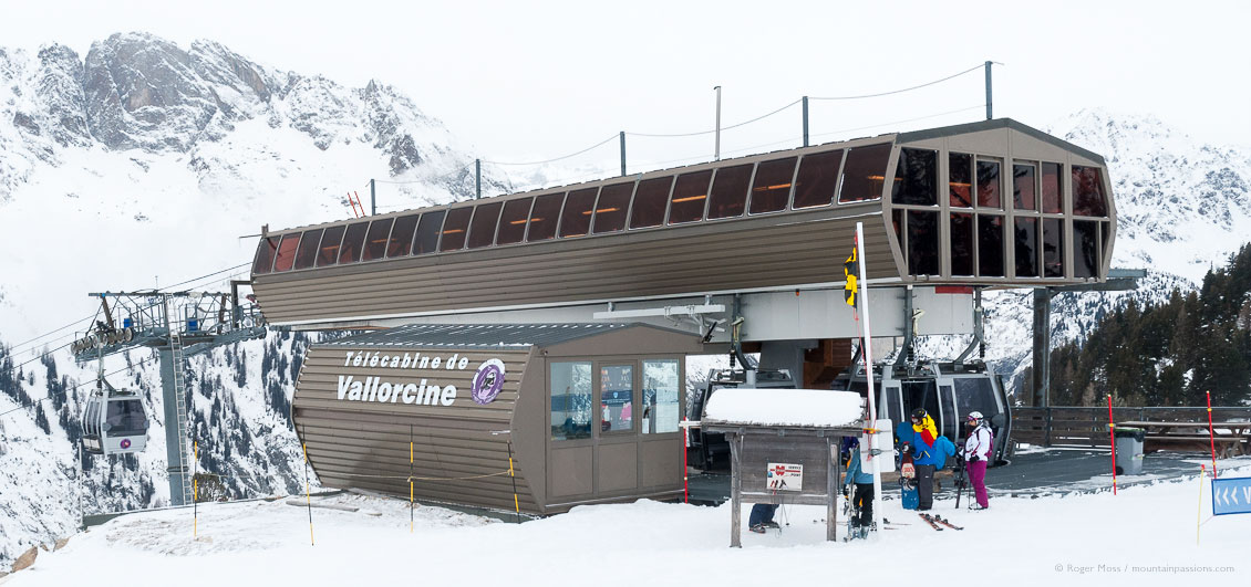 Two skiers and snowboarder beside gondola ski lift above Vallorcine