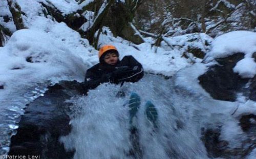 winter canyoning, person sliding down waterfall