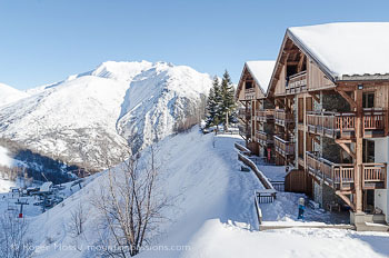 Exterior view of Goleon ski apartments, with mountains and ski lifts at Les 2 Alpes