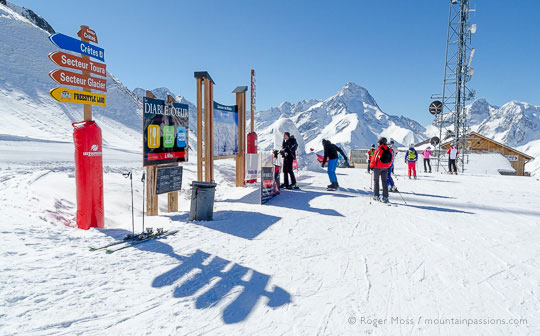 Skers looking at piste map with snowy mountainside at Les 2 Alpes