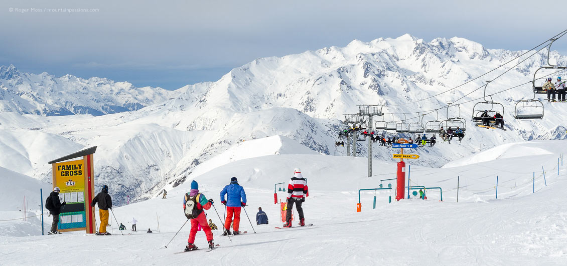 Skiers beside family fun area with big mountain view, at Les 2 Alpes