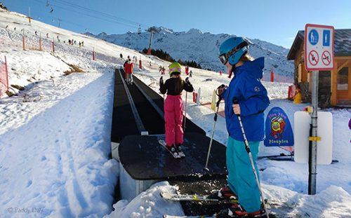 Young skiers on magic carpet ski lift, ESF ski school, Les Menuires