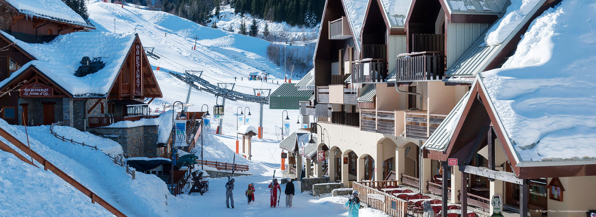 View through ski village to mountainside with visitors in Oz-en-Oisans