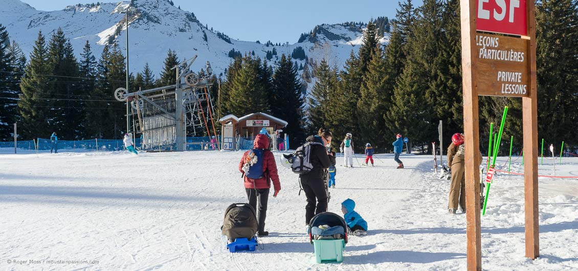 Young family walking to ski school area at Praz de Lys, French Alps.