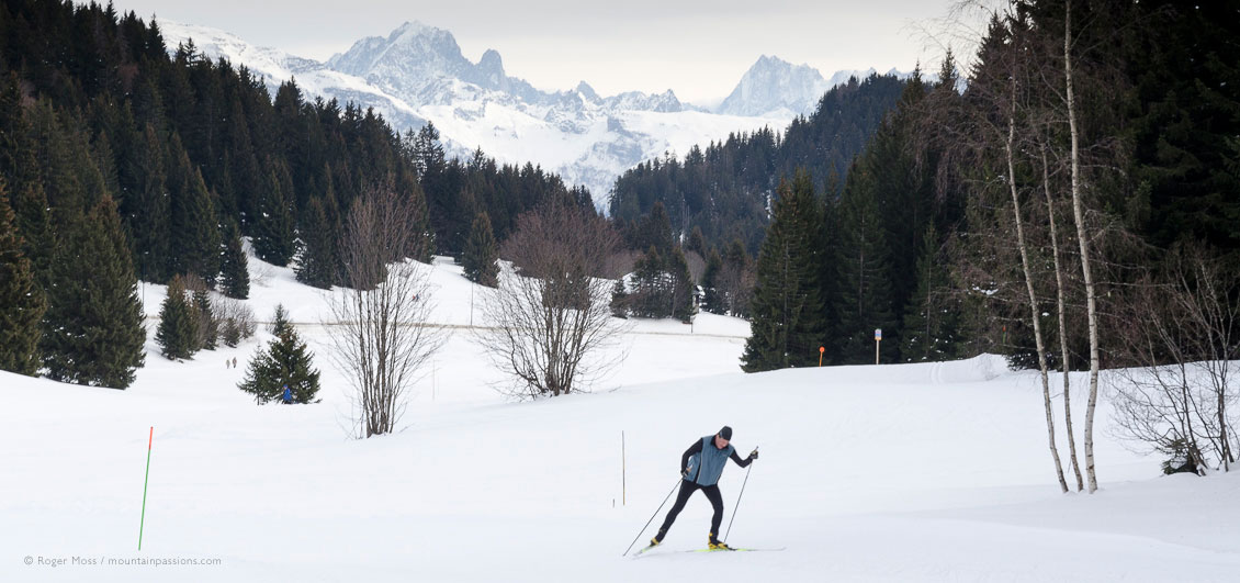 Wide view of cross-country skier with forests and mountains in background at Praz de Lys