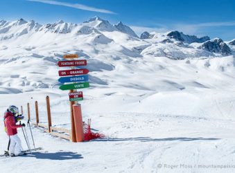 Skiers beside piste-signs at Val d'Isere, Espace Killy