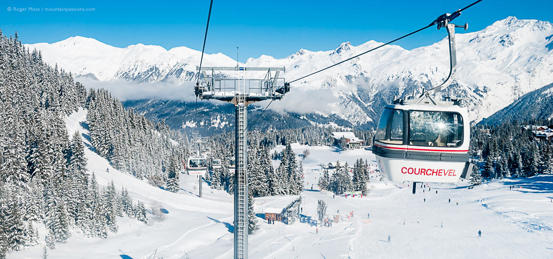 High view of gondola lift with Courchevel 1850 ski village and snow-covered mountains