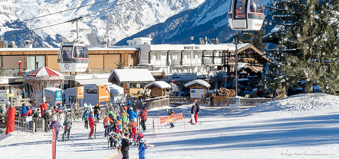 Skiers and gondola lift at Courchevel 1850 ski village, French Alps