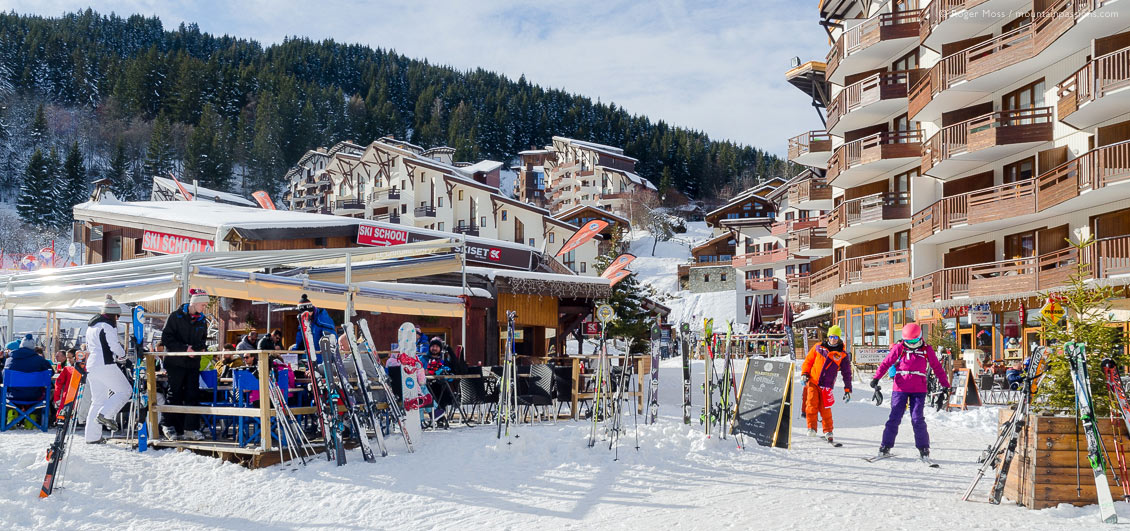 Wide view of skiers and restaurants at lunchtime in La Tania, French Alps.