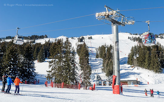 Skiers and gondola ski lift with mountainside at Courchevel, French Alps.