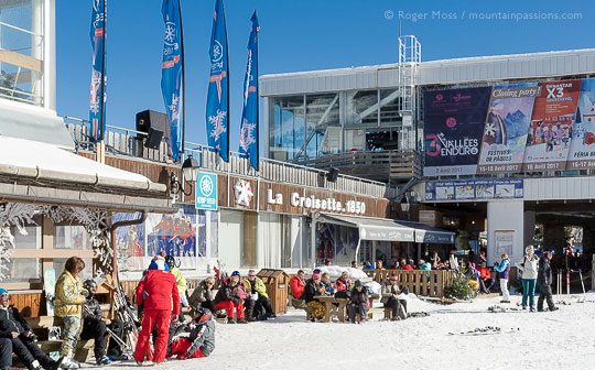 View of La Croisette, Courchevel, with skiers and ski instructor relaxing in the sun.