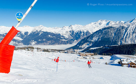 Wide view of skiers on piste heading for Couchevel 1850, French Alps.