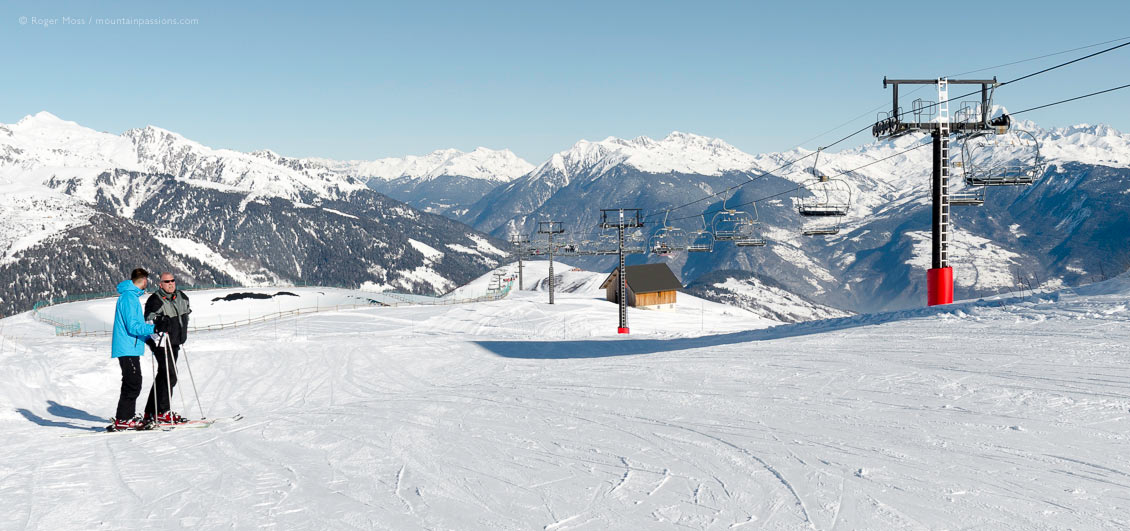 Wide view of mountainside with skiers and chairlift at Valmorel
