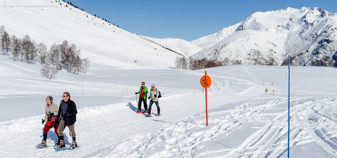 Wide view of two couples on snowshoe path at Les 2 Alpes, Isère, French Alps.