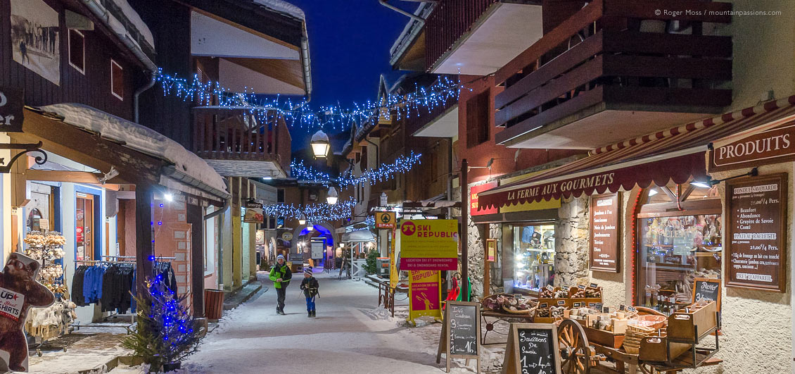 Visitors walking through colourful, car-free village heart at Valmorel, French Alps.