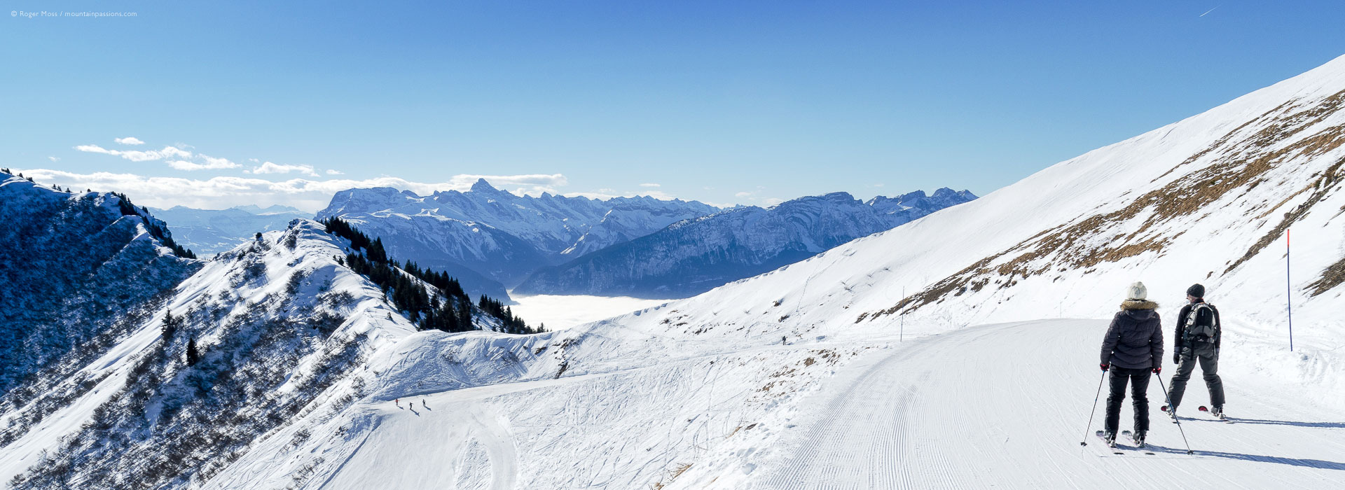 Wide view of two skiers on high mountain piste at Praz de Lys Sommand, French Alps.